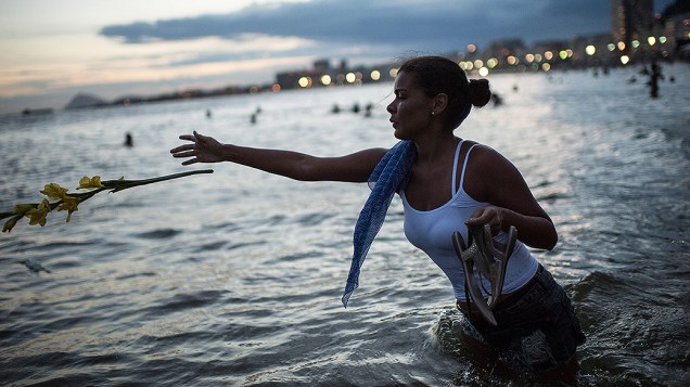 Mulher faz oferendas ao mar antes da celebração do Ano Novo em Copacabana no Rio de Janeiro