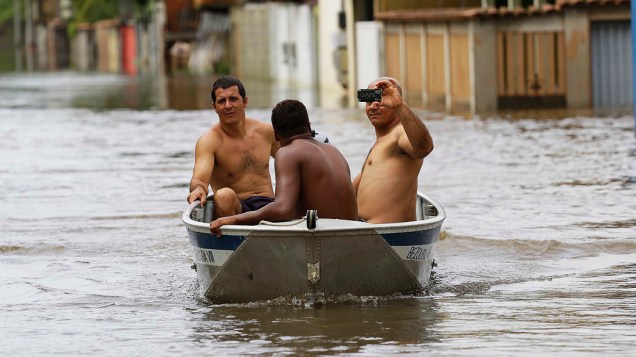 Pessoas atravessam rua de barco devido ao transbordamento de rios causado pelas fortes chuvas no municipio de Serra, próximo a Vitória, Espírito Santo