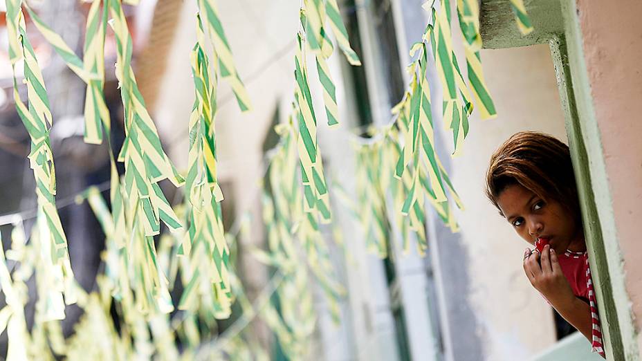 Mulher é fotografada em meio às ruas decoradas para a Copa do Mundo de 2014 na favela do Jacarezinho, no Rio de Janeiro