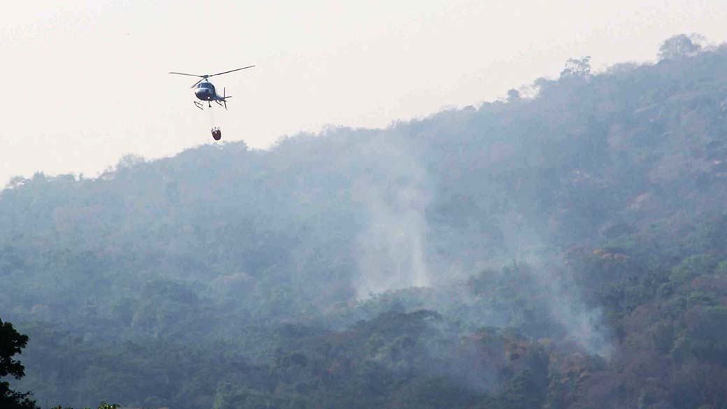 Helicóptero da Polícia Militar retira água de uma fazenda para combater incêndios que atingem a Serra da Cantareira, em São Paulo