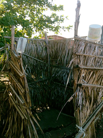 Banheiro improvisado com palha de palmeira na favela Dilma Rousseff, no Piauí