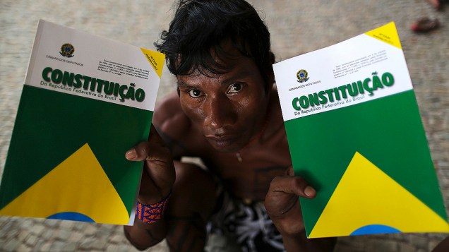 Indígena segura dois livretos da Constituição, no Palácio do Planalto, durante protesto contra a demarcação de terras indígenas e reservas no Brasil