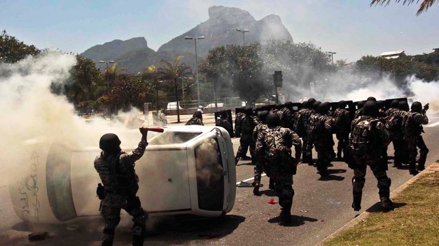 Manifestantes viram carro de emissora de TV e entram em confronto com homens da Força Nacional, nos arredores do Hotel Windsor, no Rio