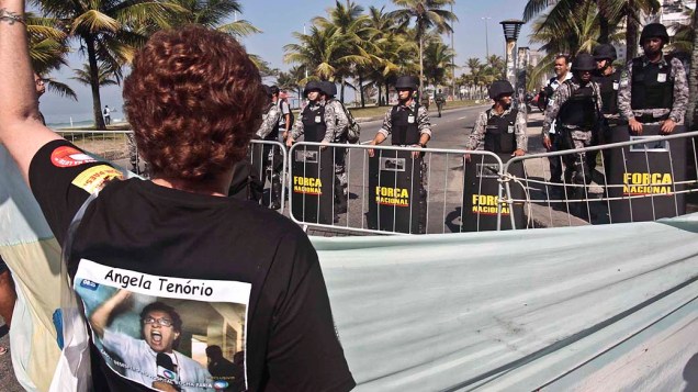 Manifestante protesta diante dos homens da Força Nacional que fazem a segurança do hotel em que será realizado o leilão de Libra, nesta segunda