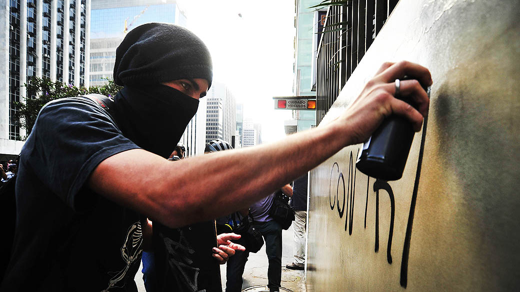 São Paulo - Integrante do Black Bloc faz pichação em muro durante manifestação na avenida Paulista