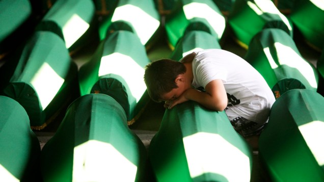 Na Bósnia-Herzegóvina, menino chora perto de caixões preparados para o enterro dos 520 corpos recentemente identificados das vítimas do massacre de Srebrenica, considerado o pior massacre da Europa desde a Segunda Guerra Mundial