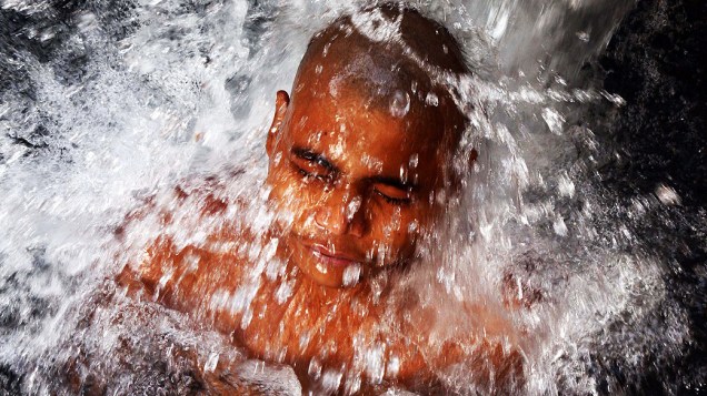 Menino se refresca em uma tubulação de água para escapar do forte calor que atinge a cidade de Allahabad, na Índia