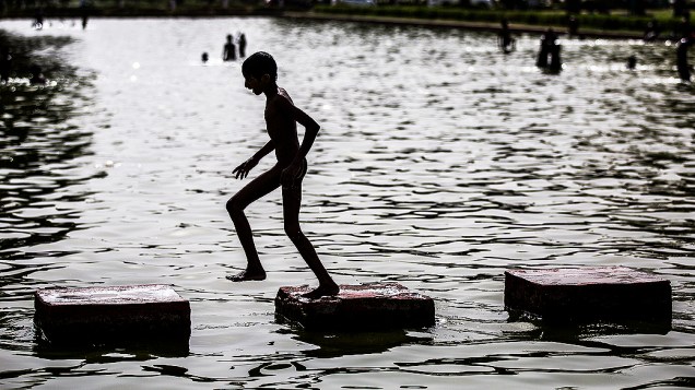 Criança se refresca em fonte de Nova Déli, na Índia, nesta quinta-feira de altas temperaturas na cidade