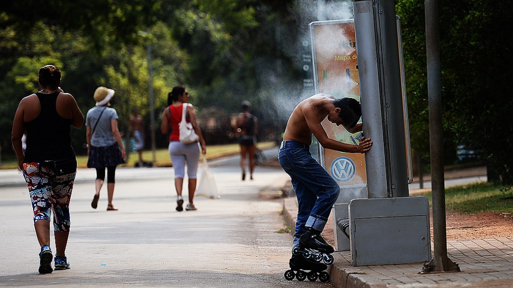 Jovem se refresca do calor no parque do Ibirapuera, em São Paulo