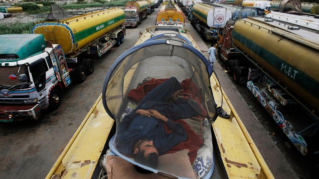 Homem dorme em cima de caminhão pipa que tranporta o combustível usado em veículos e aviões da OTAN de Karachi, no Paquistão, para o país vizinho, o Afeganistão