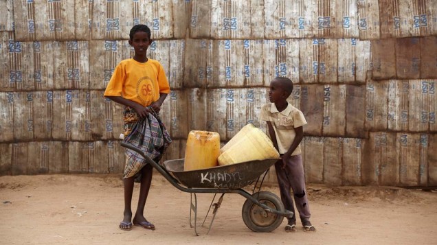 Garotos carregam recipientes com água em Dagahaley, no campo de refugiados de Dadaab, Quênia