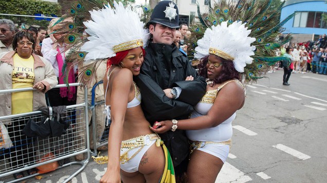 Foliãs brincam com guarda durante o festival de Notting Hill, que leva milhões de pessoas às ruas, em Londres. O evento é inspirado em festas do Caribe é considerado o maior carnaval de rua da Europa