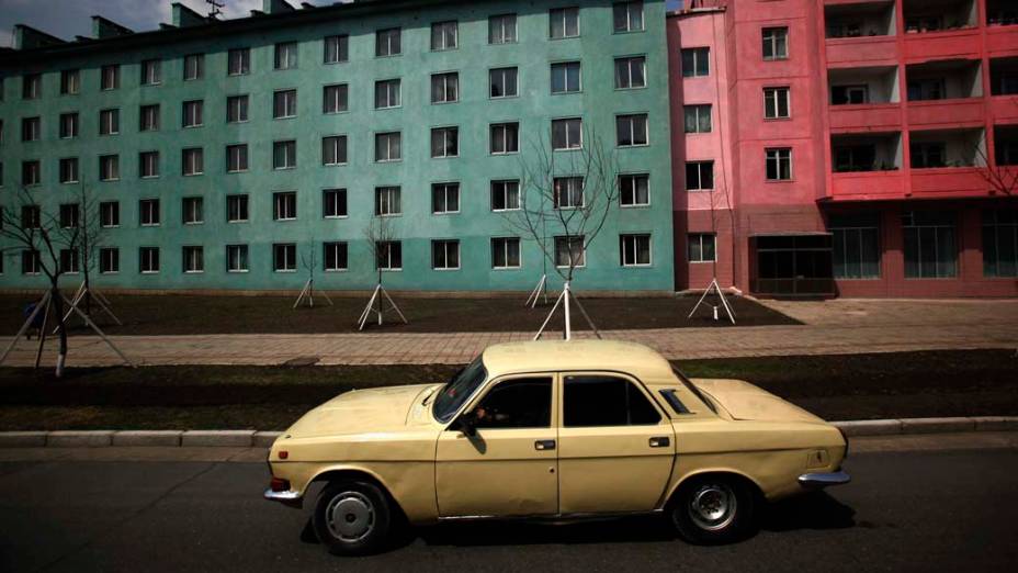 Carro passa por prédios residenciais em Pyongyang, na Coreia do Norte