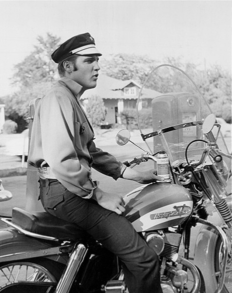 Outra foto de Elvis com sua Harley-Davidson KH, modelo precursor da atual Sportster. Além da cor vermelha, a moto exibia detalhes em branco no tanque de combustível e um enorme para-brisa