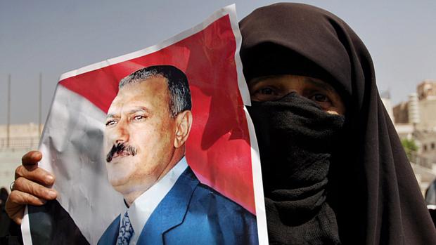 Partidária de Saleh exibe cartaz com a foto do presidente, já a oposição pede a sua saída