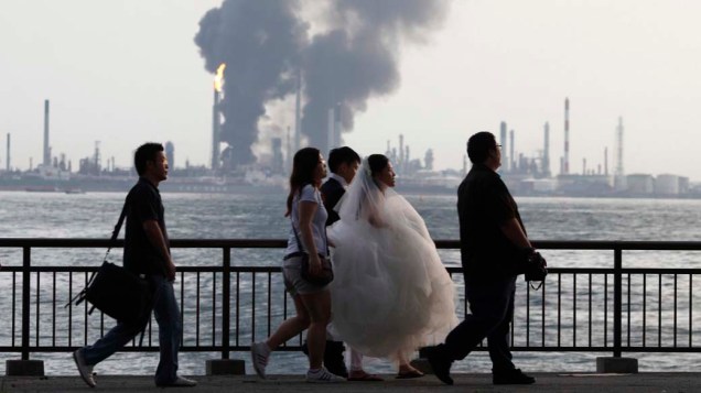 Casal de noivos passam com seus fotógrafos por refinaria que pega fogo em Cingapura