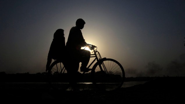 Casal anda de bicicleta na margem do rio Ravi, no Paquistão