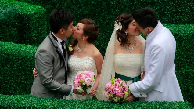 Casais chineses se beijam, após o casamento no Dia dos Namorados