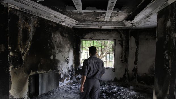 Homem caminha por casa queimada durante protestos em Deraa