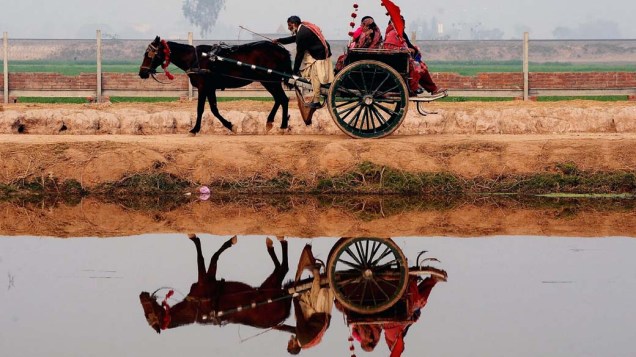 Aldeões paquistaneses viajam em carroça nos arredores de Lahore, Paquistão