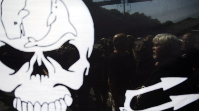 Ativista Paul Watson, fundador e presidente da "Sea Shepherd Conservation Society", visto através de uma bandeira durante manifestação em Berlim. Ele é acusado de colocar uma tripulação de um navio pesqueiro em risco devido sua luta pela preservação de espécies marinhas