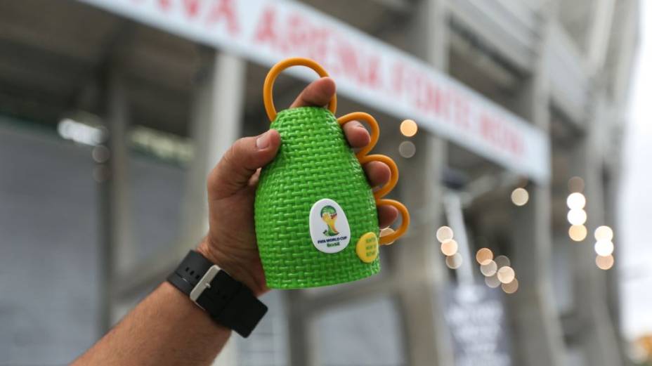 Torcedor segura uma caxirola diante da Arena Fonte Nova, em Salvador