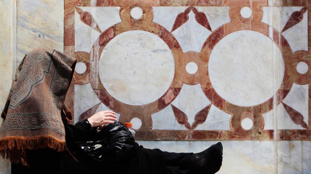 Mulher palestina sentada do lado de fora do Domo de Pedra, durante o mês sagrado do Ramadan na Cidade Velha de Jerusalém