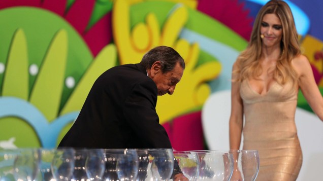 Fernanda Lima observa o ex-jogador uruguaio, Gigghia sorteando uma bolinha