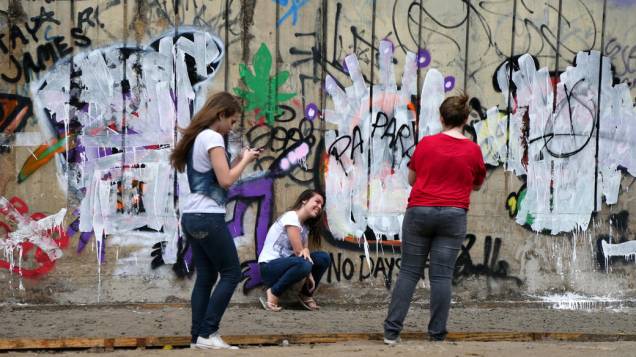Fãs tiram fotos ao lado dos grafites de Justin Bieber, após um fotógrafo pintar o muro de branco