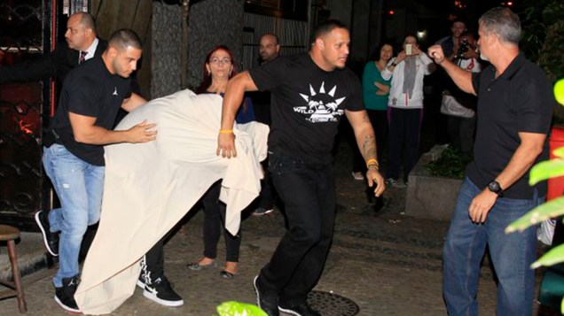 Justin Bieber, coberto por um lençol branco sai de uma boate em Ipanema, no Rio de Janeiro