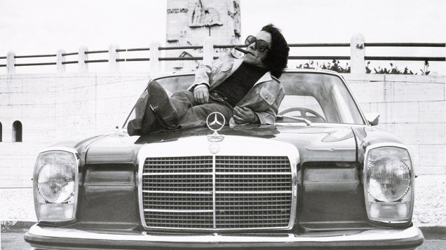 O cantor Nelson Ned sentado no capô de um Mercedes, em 1973