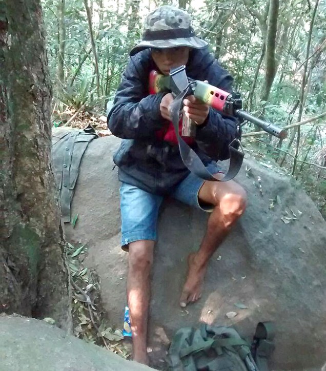 O criminoso identificado como CH exibe um fuzil estilizado nas cores do Reggae na mata da favela
