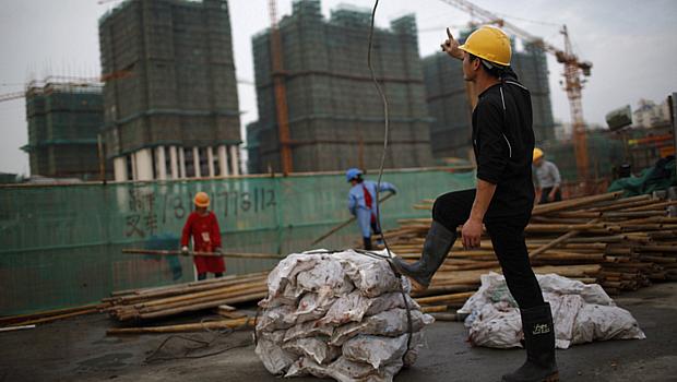 Funcionário orienta trabalhadores em um canteiro de obras no centro financeiro de Xangai