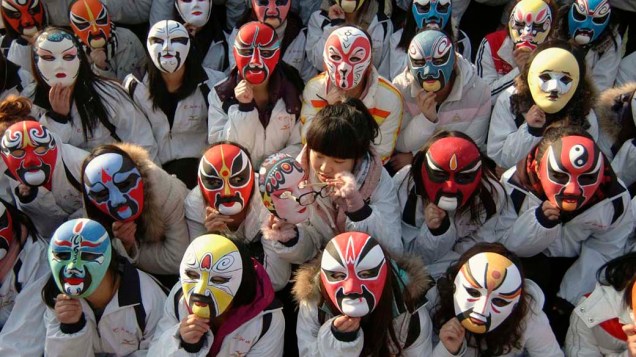 Estudantes com máscaras em evento para promover a ópera Peking em universidade de Liaocheng, China