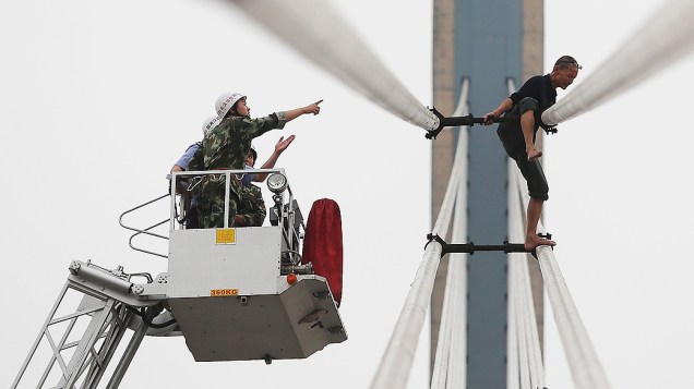Equipes de resgate tentam impedir um homem de cometer suicídio em uma ponte em Wuhan, na província de Hubei, na China.