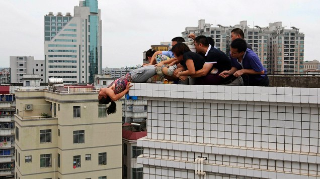 Foto divulgada nesta segunda-feira (20) mostra parentes impedindo uma mulher de cometer suicídio em Zhanjiang, na China. Segundo a imprensa local, ela tentou pular do prédio após matar o sobrinho durante uma disputa familiar, o caso aconteceu na última terça-feira (14)