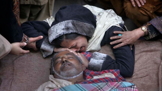 Mulher chora no leito de seu tio morto por problemas do coração em Lahore, Paquistão