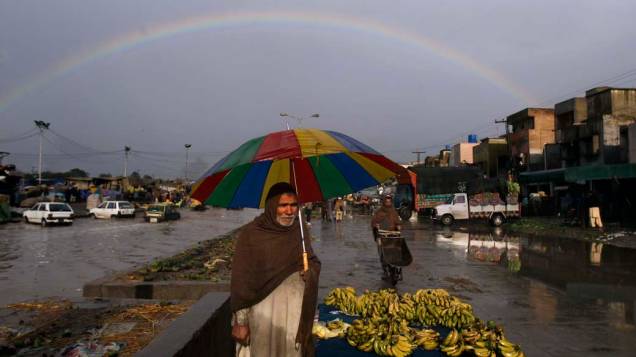 Paquistanês se protege da chuva no centro de Islamabad