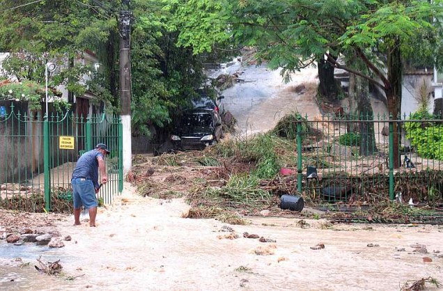Morador tenta retirar a lama trazidas pela água da chuva na rua Tupis, no bairro São Francisco, em Niterói.