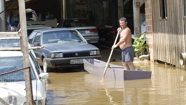 Morador usa barco no alagado bairro Nova Brasília, em Joinville