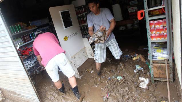Trabalhadores limpam loja após alagamentos em Teresópolis, Rio de Janeiro - 13/01/2011