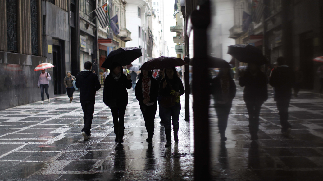 Pessoas se protegem da chuva e do frio que atinge a cidade de Sao Paulo, durante a manhã no centro da capital