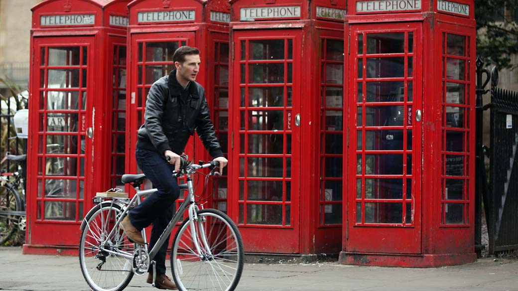 Rapaz passa por cabines telefonicas em Cambridge, na Inglaterra