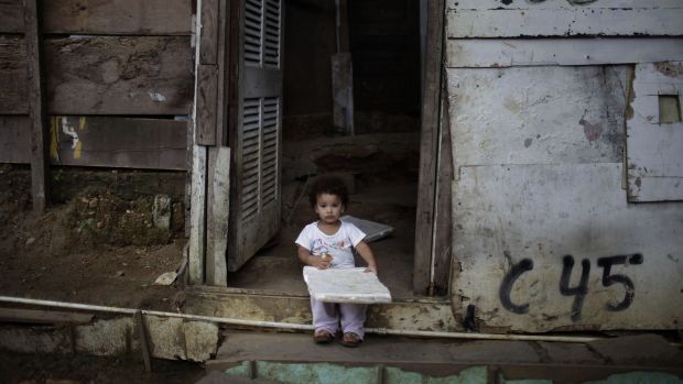 Menino come um pedaço de pão na favela Cidade de Deus. A desigualdade social continua sendo um problema sério no Brasil