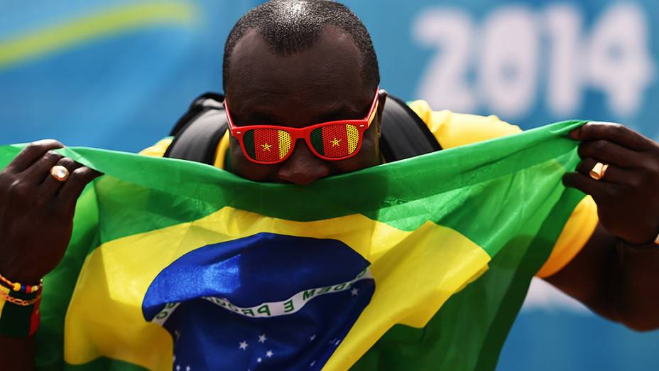 Torcedor segura a bandeira do Brasil antes do jogo contra Camarões no Mané Garrincha, em Brasília