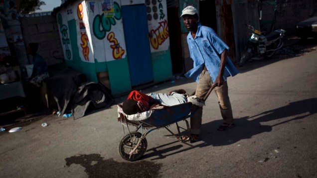 Homem carrega garoto com cólera para hospital improvisado pelos Médicos Sem Fronteiras em Porto Príncipe, Haiti