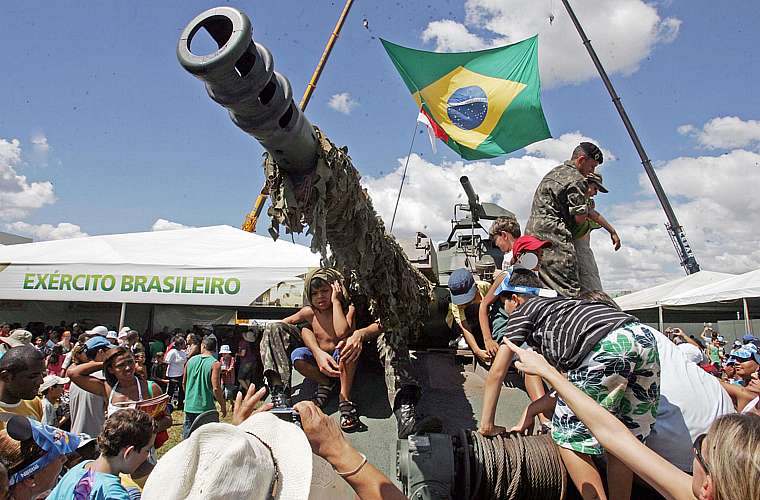 Crianças brincam com o tanque de guerra do exército brasileiro.