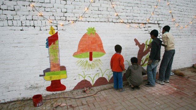 Crianças pintam mural em comemoração ao Natal, no Paquistão. A segurança do país foi reforçada para evitar possíveis ataques contra igrejas católicas - 24/12/2011