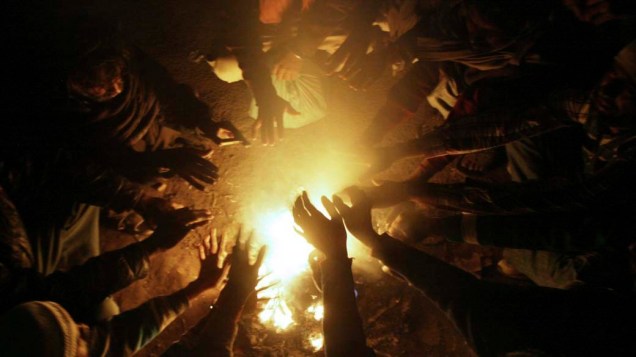Indianos se juntam ao redor de uma fogueira para se aquecer e se proteger do frio em Amritsar, Índia