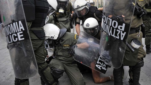 Policiais imobilizam manifestante durante protesto em Atenas, Grécia